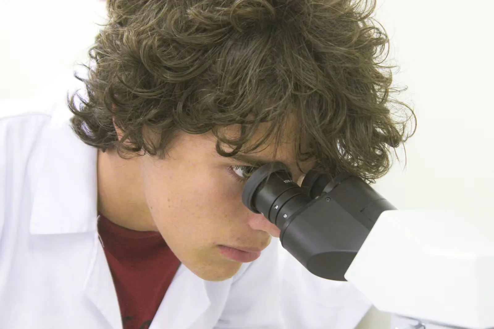 Junge Wissenschaftlerin schaut im Labor durch ein Mikroskop