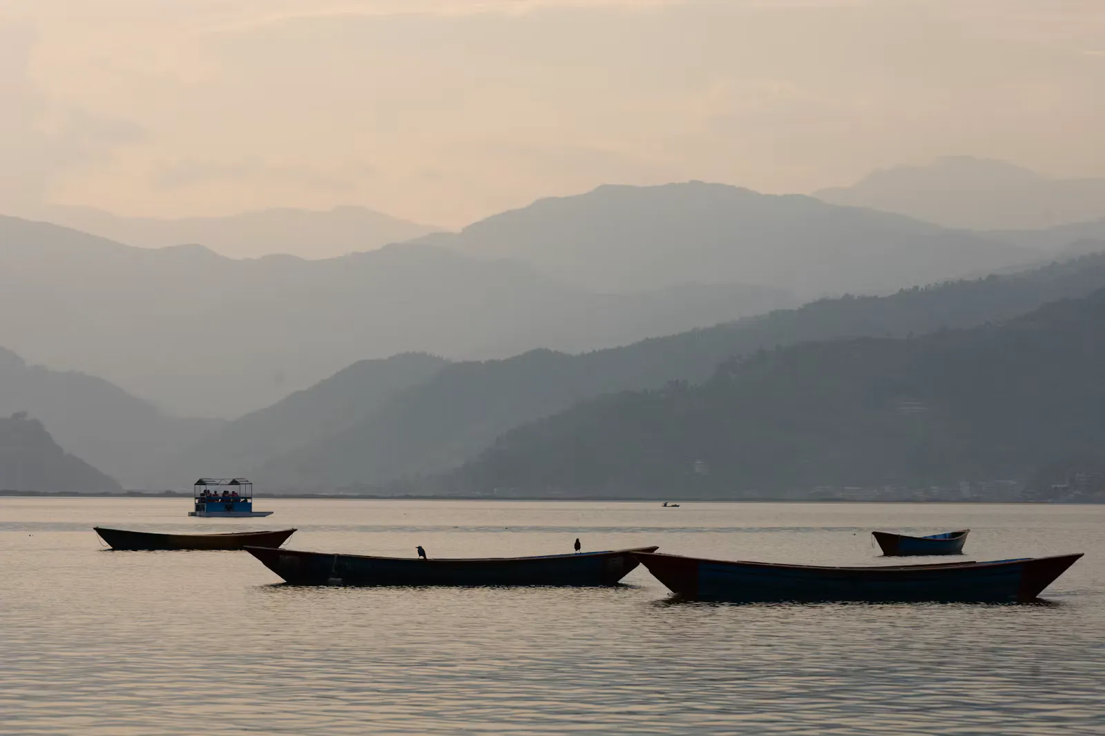 Ruderboote liegen auf dem ruhigen Phewa-See in Pokhara vor Bergen, Symbolbild für die beste Reisezeit in Nepal im Herbst