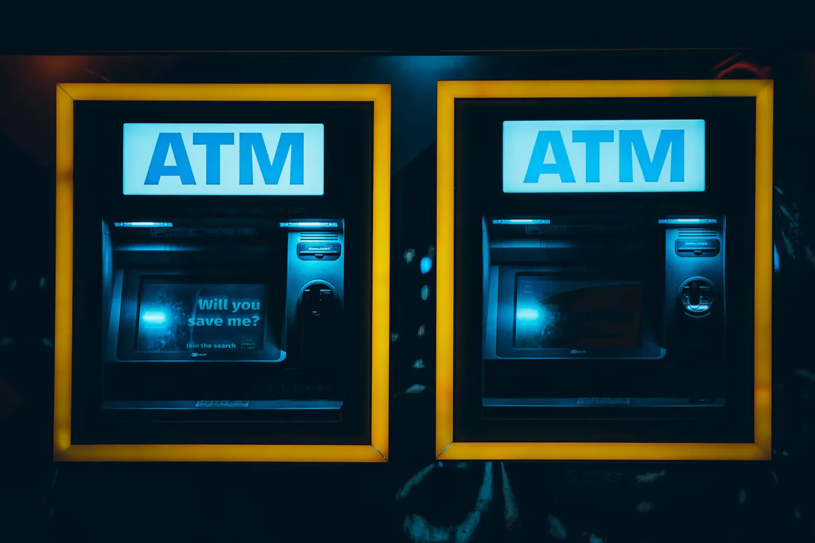 Two illuminated ATMs side by side in yellow frames