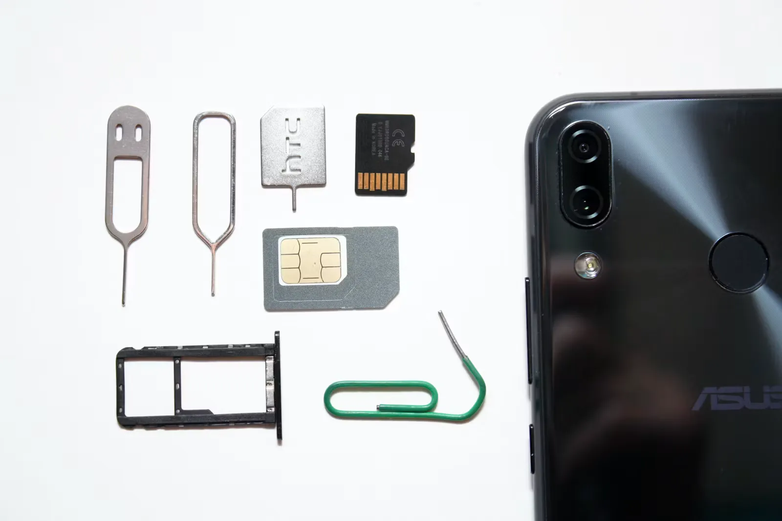 Smartphone mit eingelegter SIM-Karte auf einer Tischplatte, daneben das SIM-Werkzeug