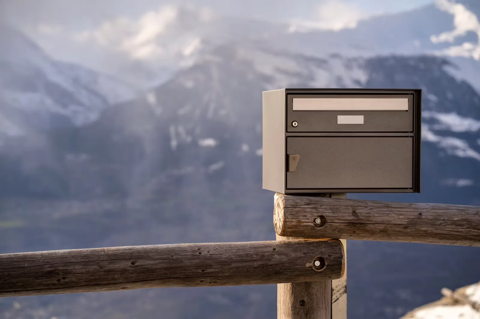 Briefkasten aus Metall an einem Holzzaun