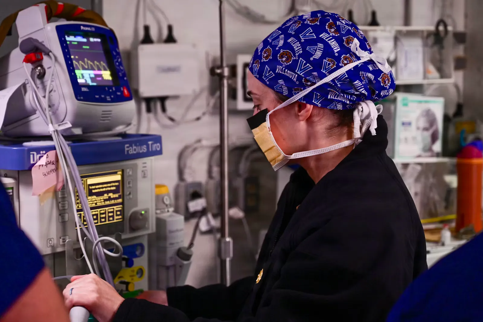 A medical professional in scrubs and mask operating equipment