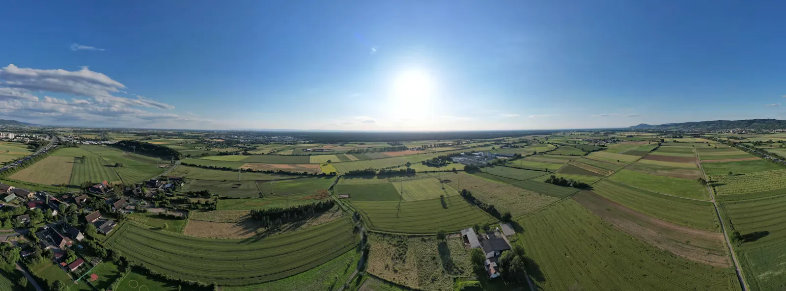 Luftpanorama einer ländlichen Region mit Feldern, Wiesen und einem Dorf am Rand, Zielgebiet der hausärztlichen Versorgung in Nordrhein-Westfalen
