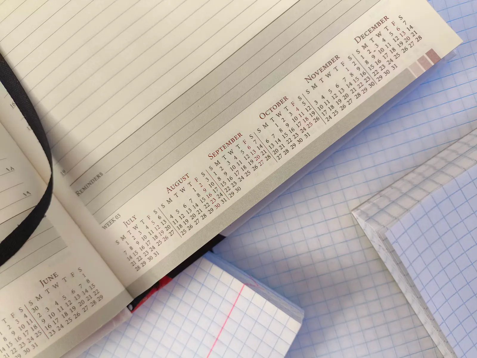 Open planner showing the calendar months from June to December on top of grid paper notebooks