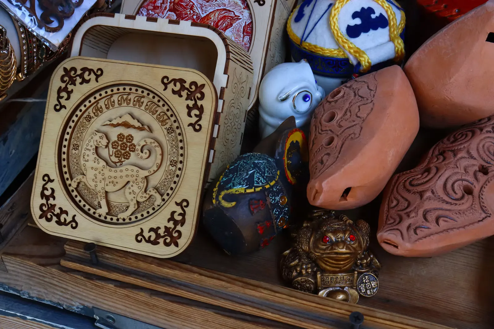 Holzkiste mit Ornamenten, Tonfiguren und kleinen Glücksfiguren auf einem Souvenirstand, Symbolbild für Mitbringsel aus dem Auslandspraktikum