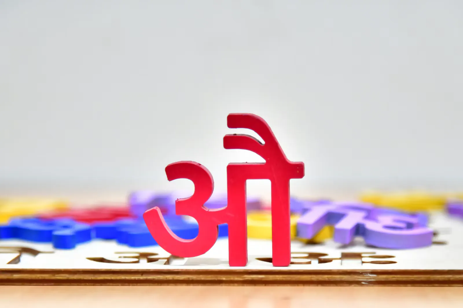 A red wooden Devanagari letter standing among colourful alphabet pieces, a reminder that NEET Hindi medium students learn science in two scripts