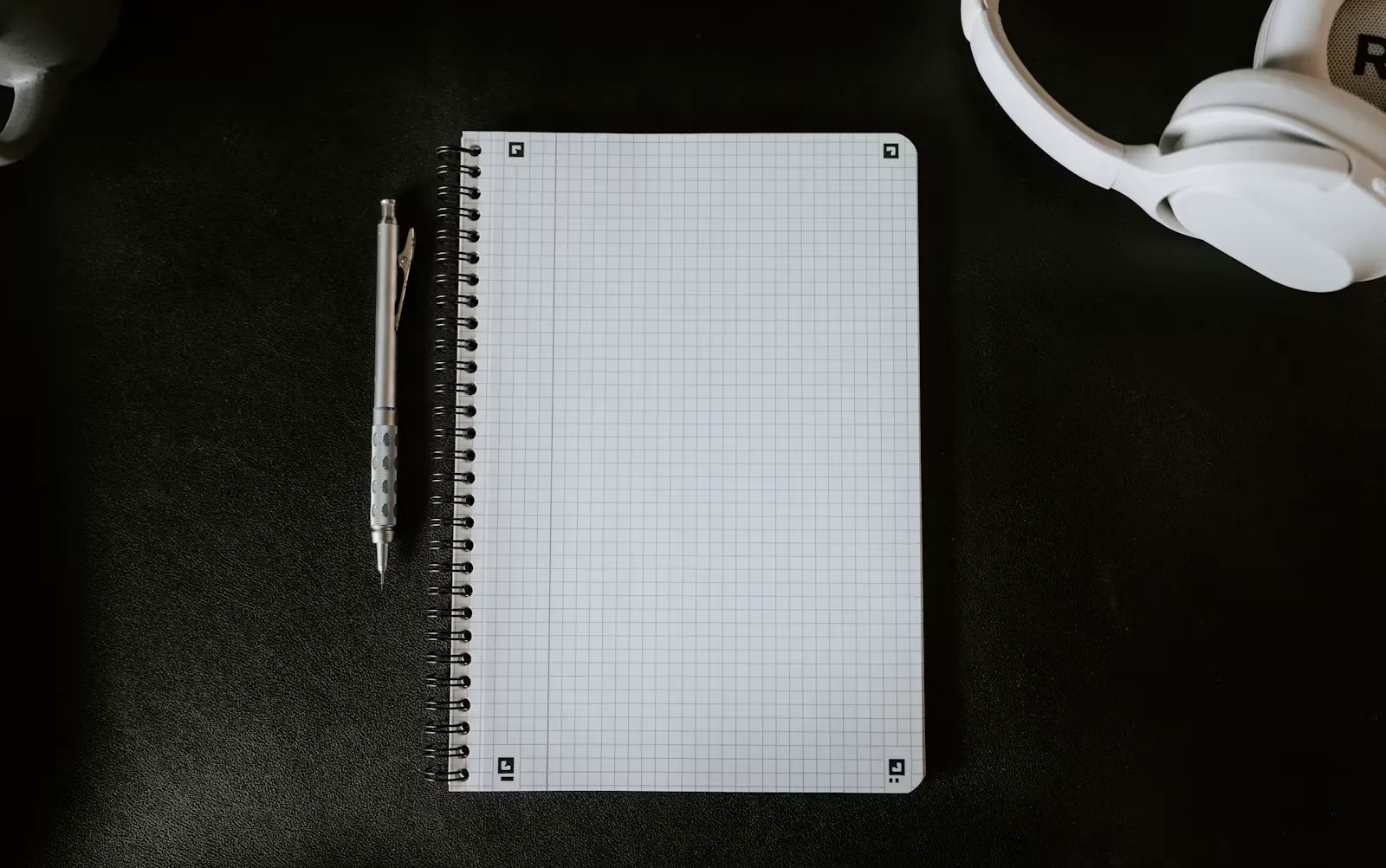 A notepad with a pen on it beside a mug