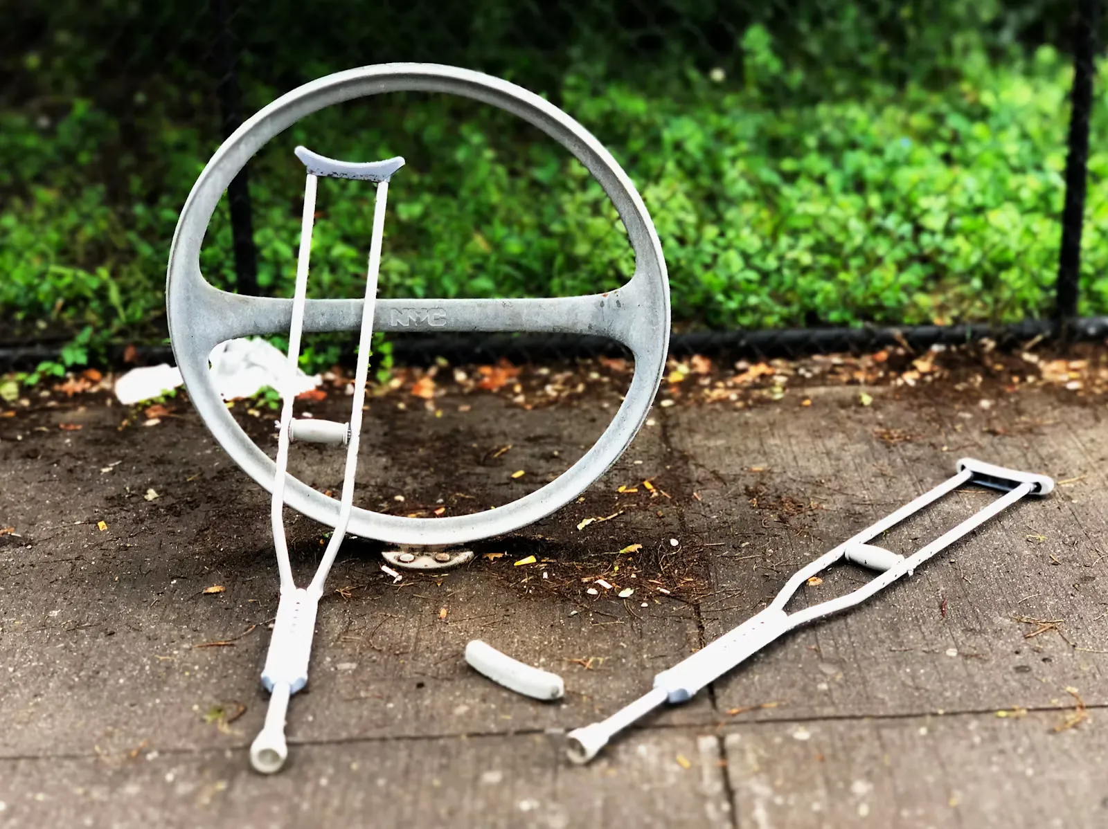 Zwei weisse Gehstützen liegen auf einem Trottoir neben einem runden Veloständer