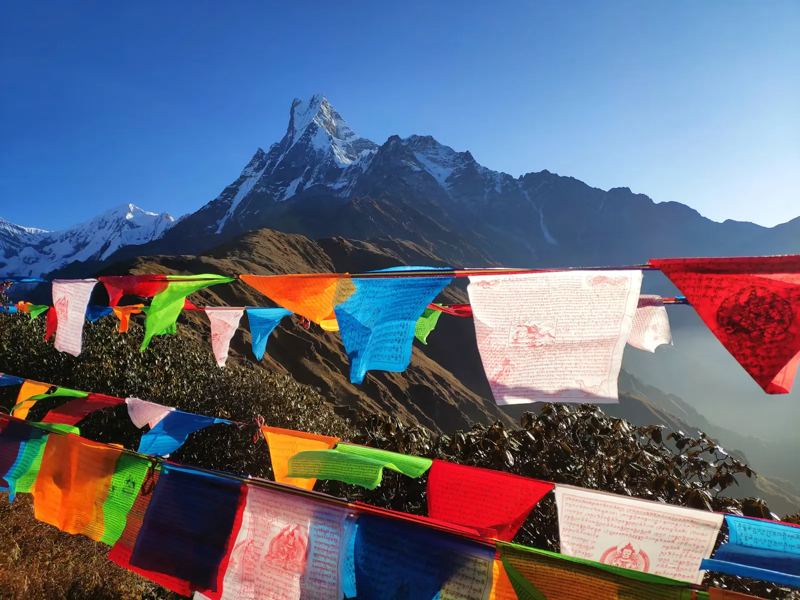 Prayer Flags ueber einem Bergpanorama in Nepal, Symbolbild fuer die Akklimatisation auf einem Trekking im Himalaya