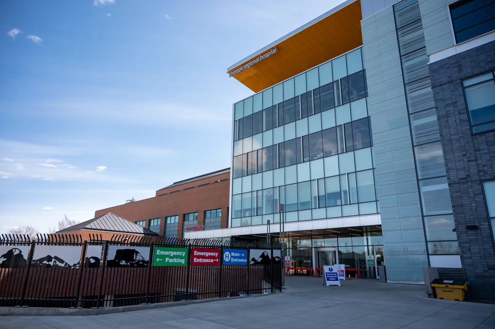 Modernes Spitalsgebäude mit Glasfassade und Hinweistafeln zur Notaufnahme unter blauem Himmel – Symbolbild für das Klinisch-Praktische Jahr im Spital