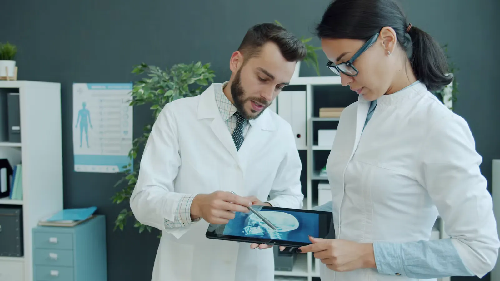 Two clinicians in white coats looking together at a head scan displayed on a tablet during a stroke care discussion