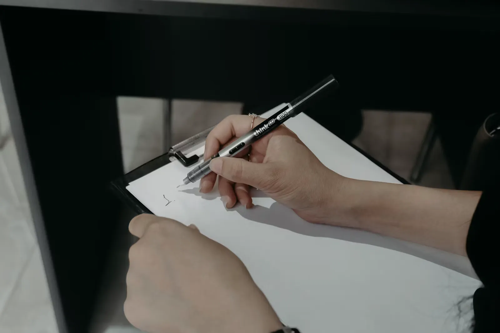 Healthcare professional writing on a clipboard at a desk, representing the written request needed to secure paid educational leave abroad