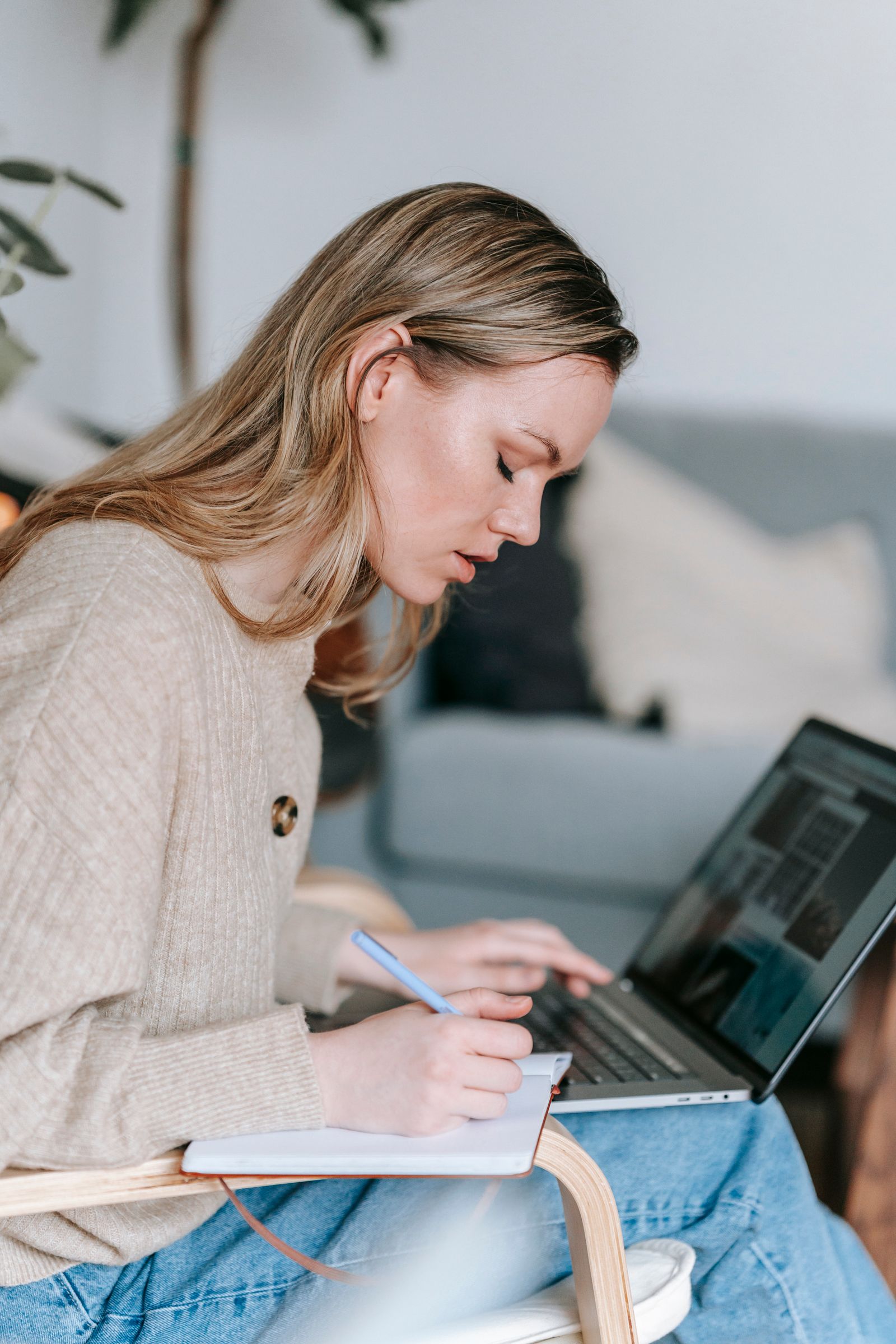 Student writing notes in a planner beside an open laptop, researching and budgeting for the cost of studying medicine abroad