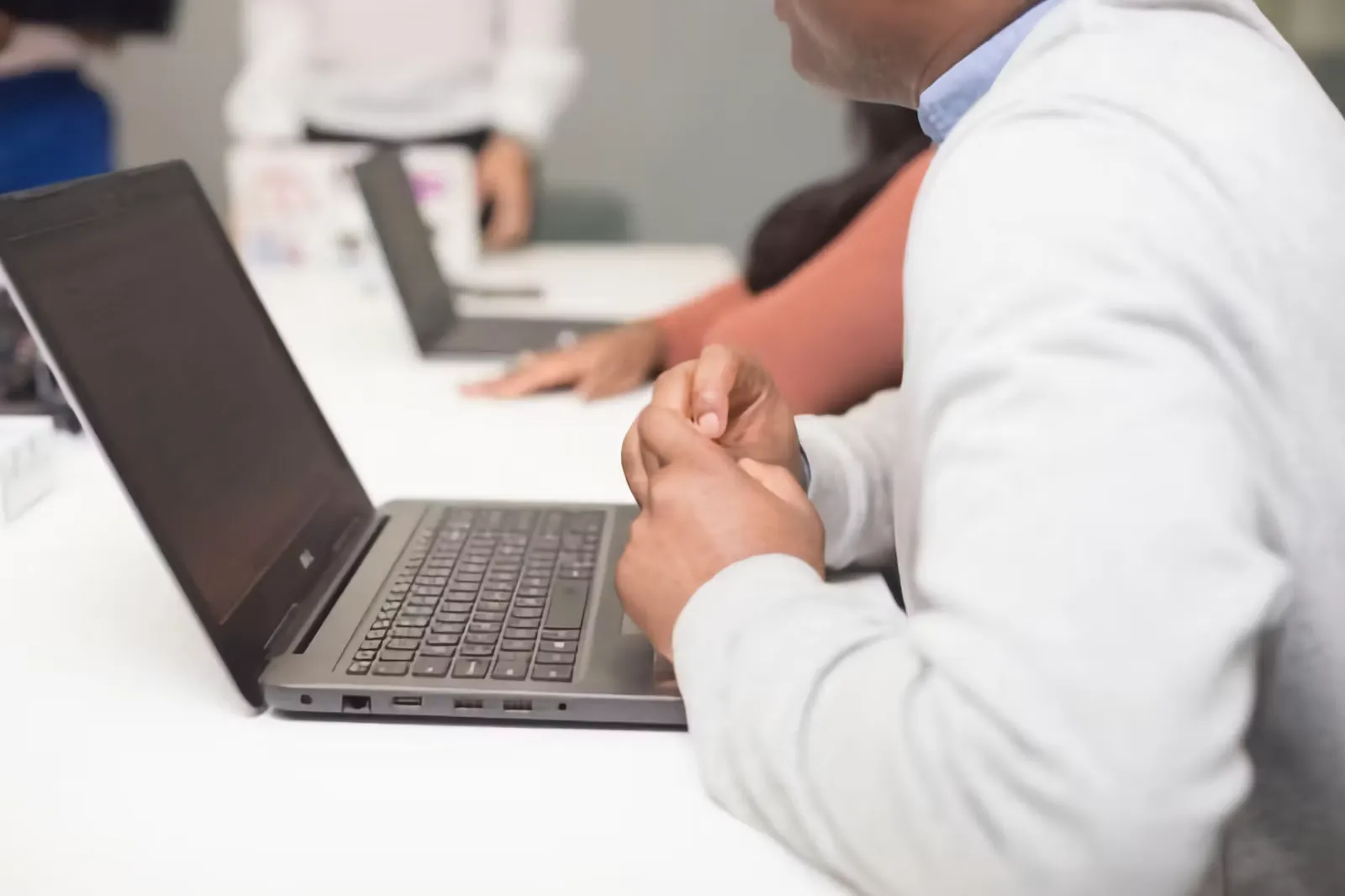 A doctor sitting at a table working on a laptop computer, preparing an online application