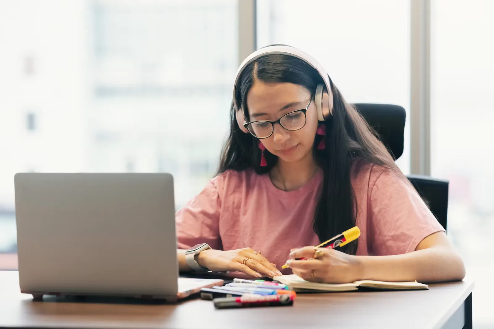Student wearing headphones concentrating at a desk while studying, the kind of practice the OET listening sub-test needs