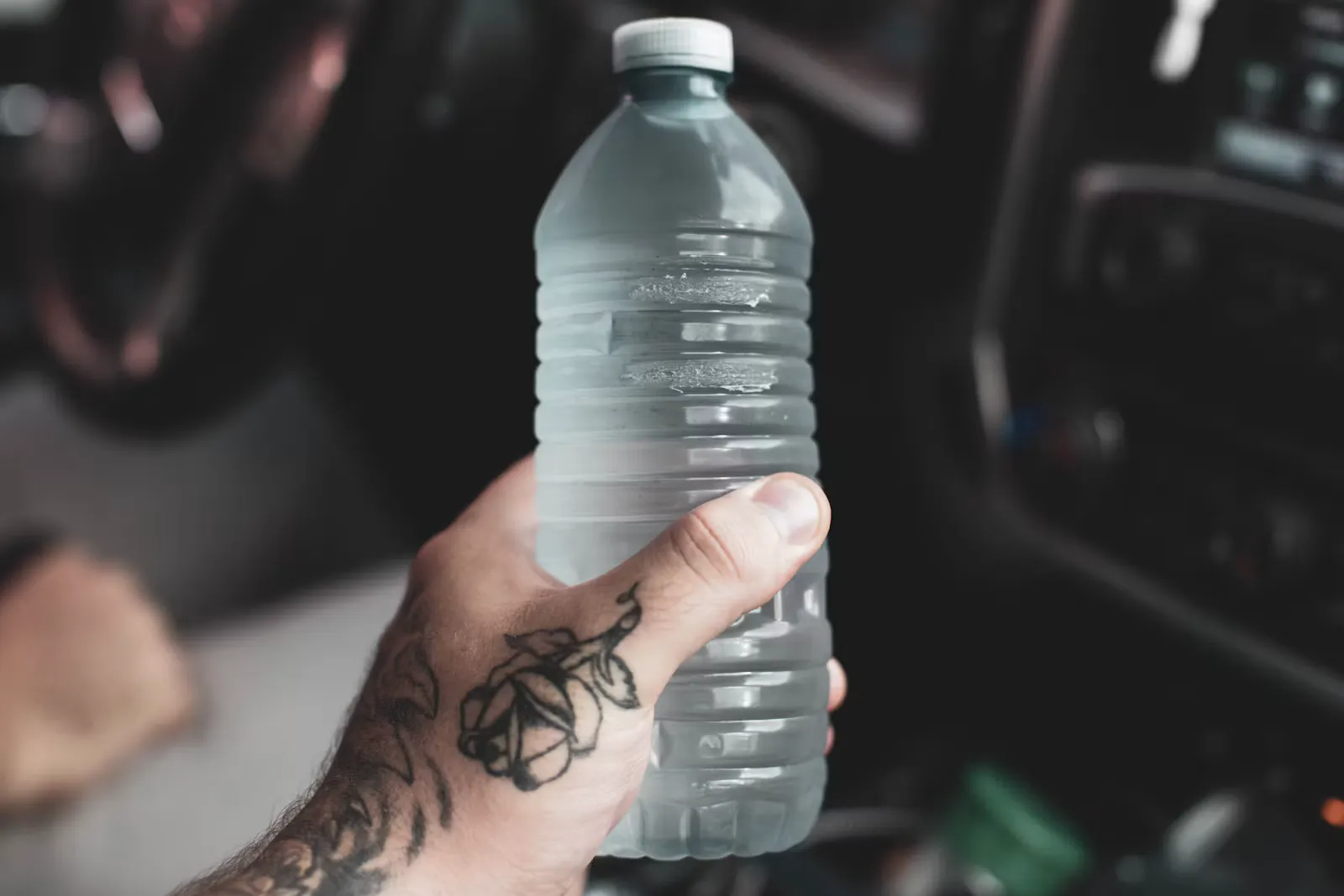 Hand hält eine verschlossene Plastikflasche mit Trinkwasser, Schutz vor Reisedurchfall durch versiegeltes Flaschenwasser