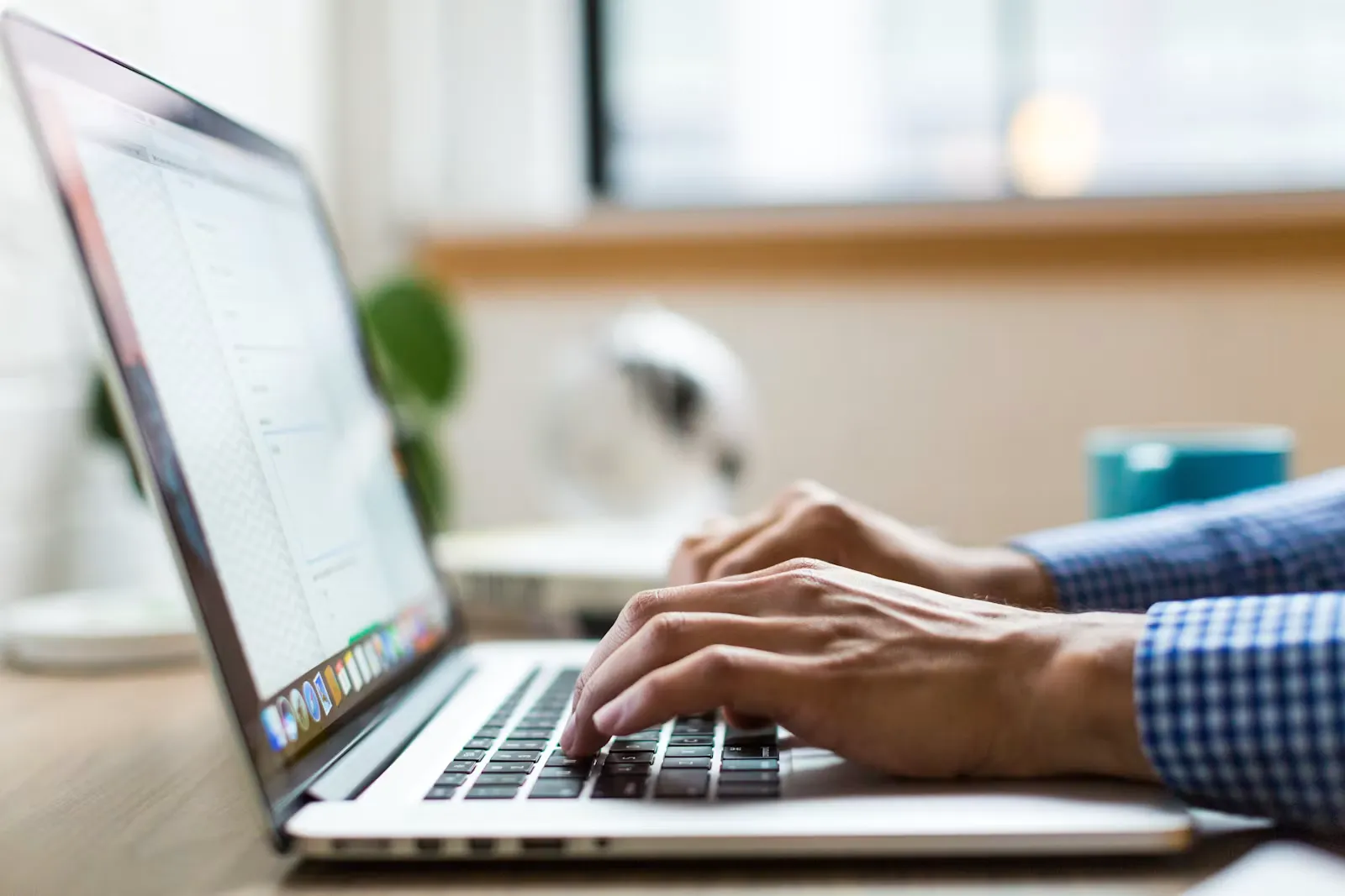 Hands typing on a laptop keyboard beside a window, representing the shift from OMR sheets to on-screen answering in a computer-based NEET