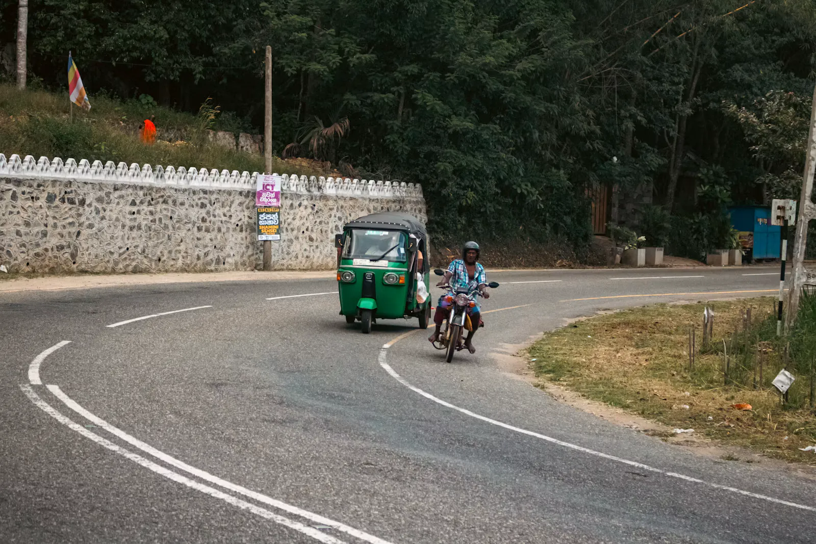 Tuk-Tuk und Motorrad auf einer kurvigen Landstrasse in Südasien, typischer Verkehr rund um einen Praktikumsort