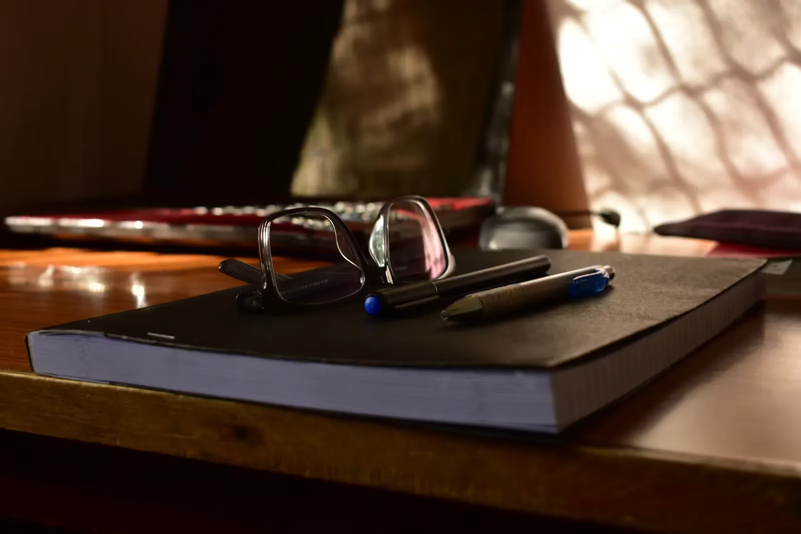 Glasses and pens resting on an open notebook
