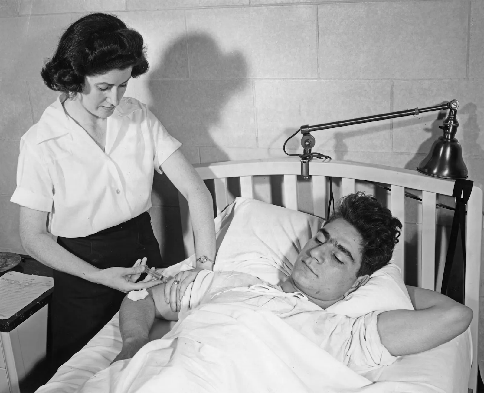 Pflegekraft verabreicht einem Patienten im Bett eine Injektion