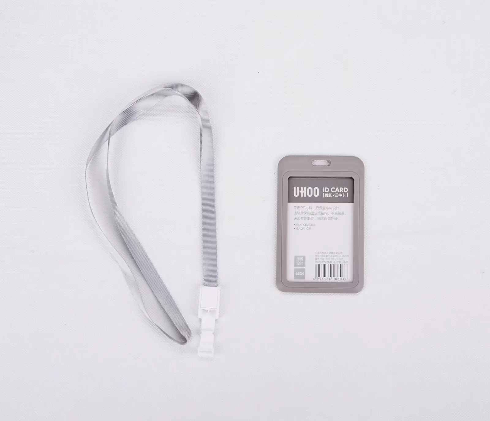 Grey lanyard next to an empty ID card holder on a white surface