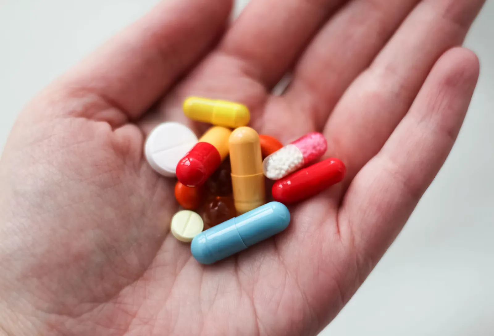 Offene Handfläche mit bunten Tabletten und Kapseln, Symbolbild für den Umgang mit Antibiotika und multiresistente Keime im Praktikum