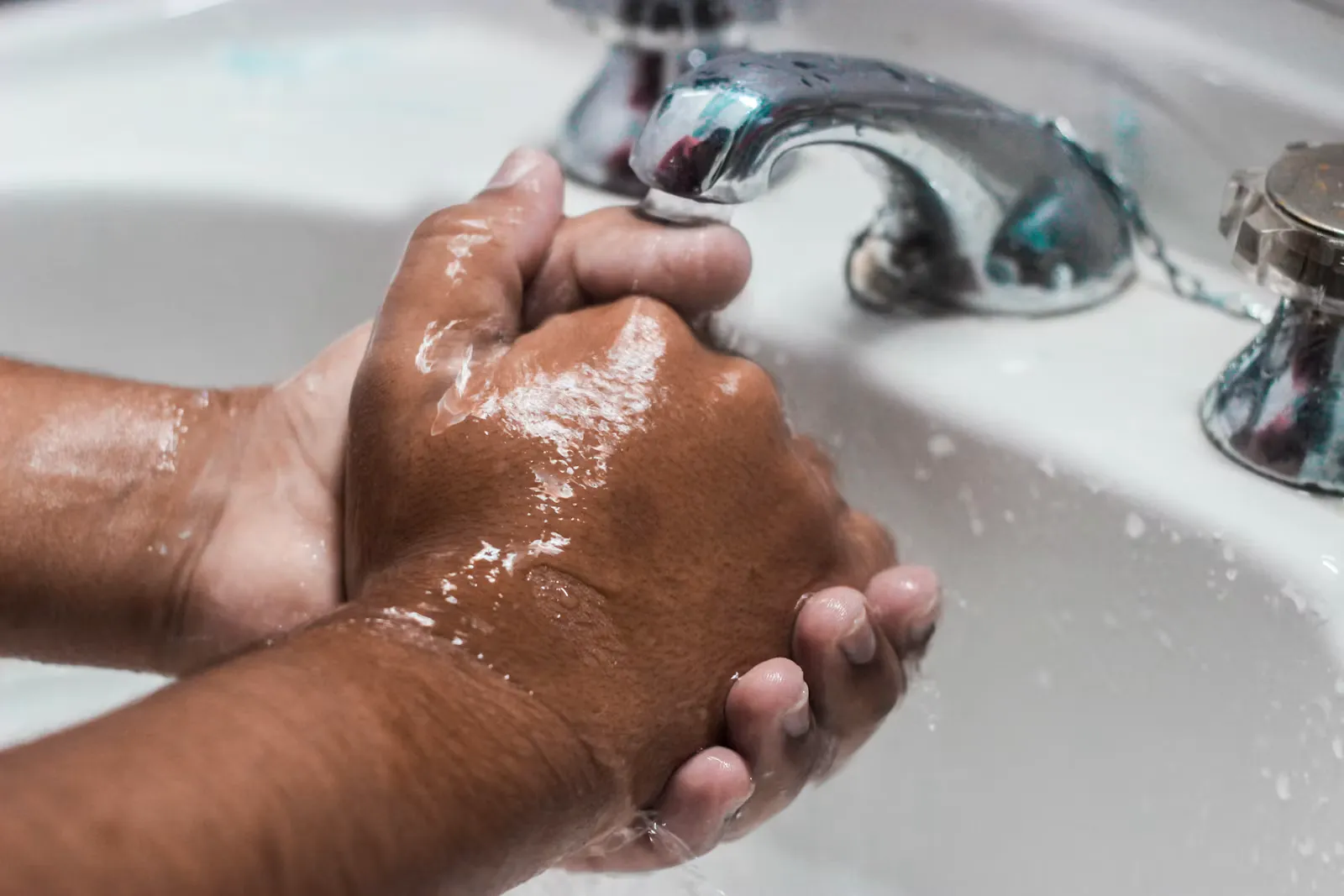 Person wäscht sich an einem Waschbecken gründlich die Hände mit Wasser und Seife, Sinnbild für die 40 bis 60 Sekunden der WHO