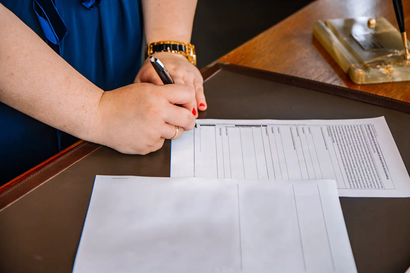Person hält einen Stift und schreibt auf ein Blatt Papier