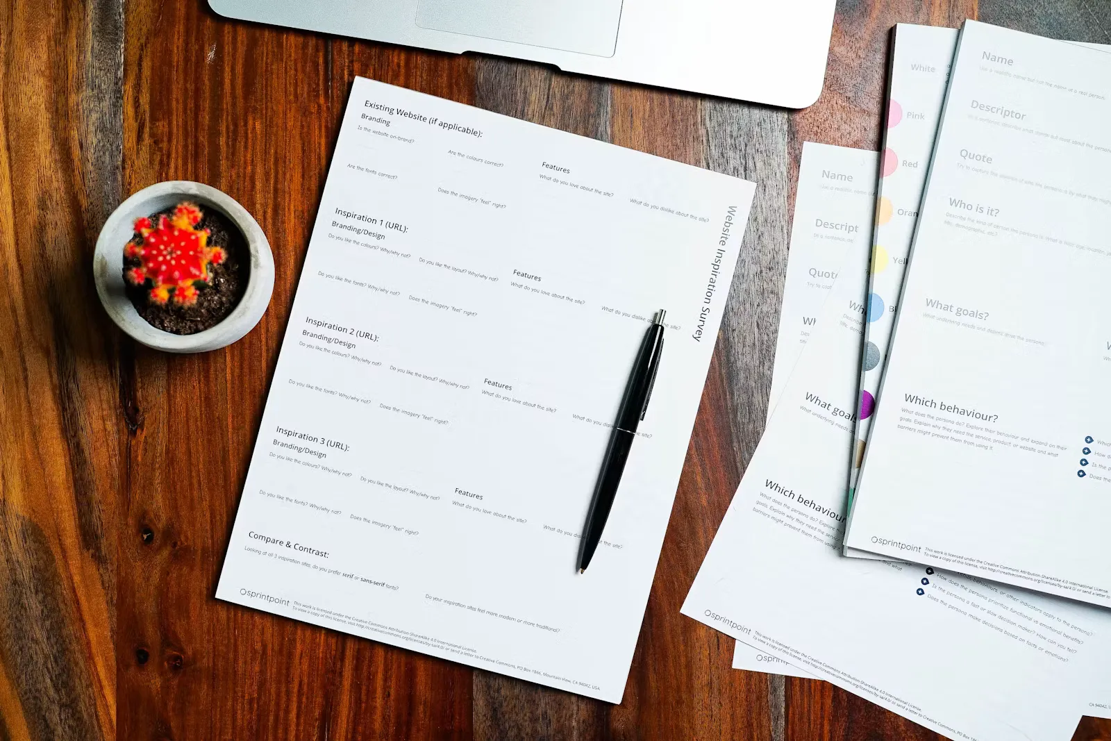 A wooden table covered with documents and a pen
