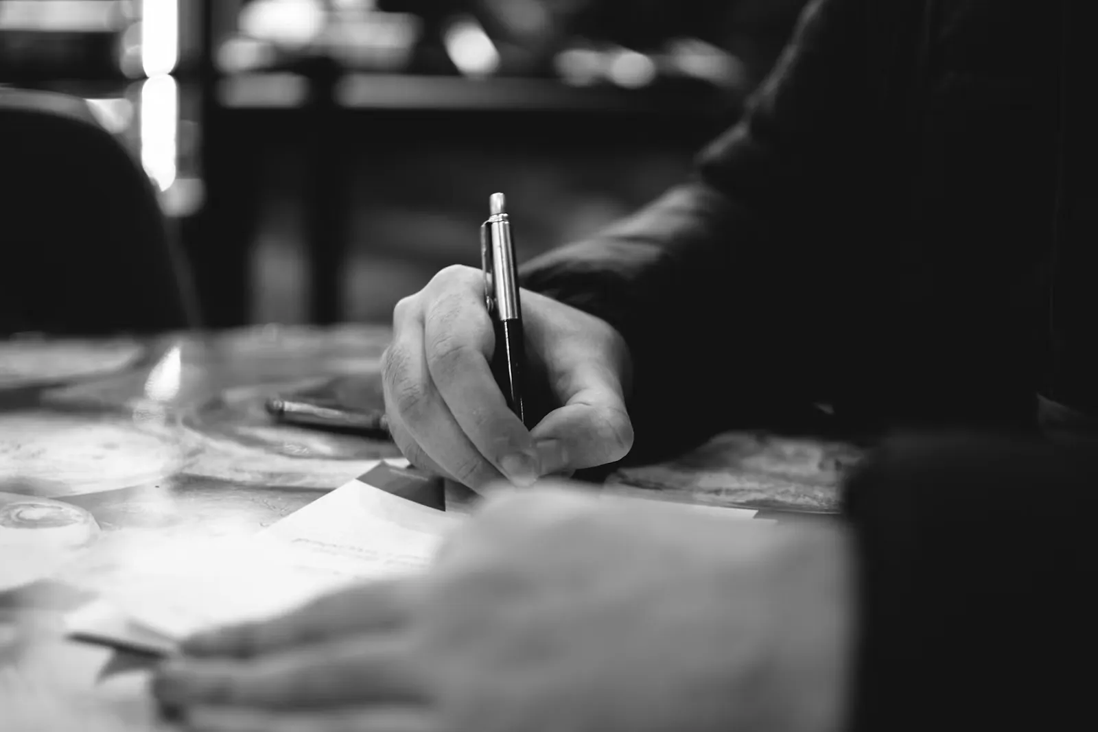 Person schreibt mit der Hand auf weißes Papier, wie beim Entwurf eines Anschreibens