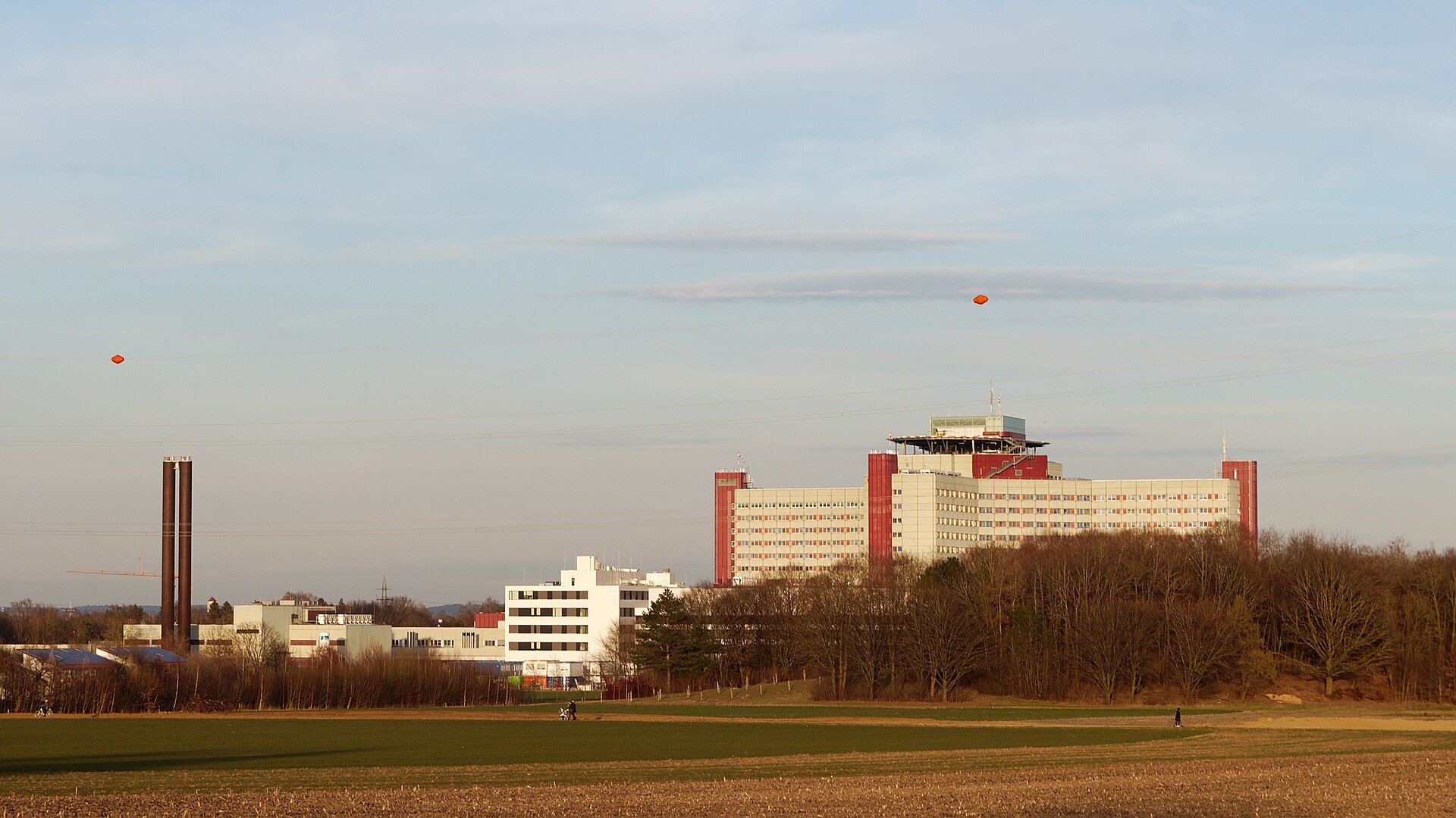 Moderner Klinikbau des Universitätsklinikums Augsburg mit Glasfassade und Vorplatz an einem sonnigen Tag