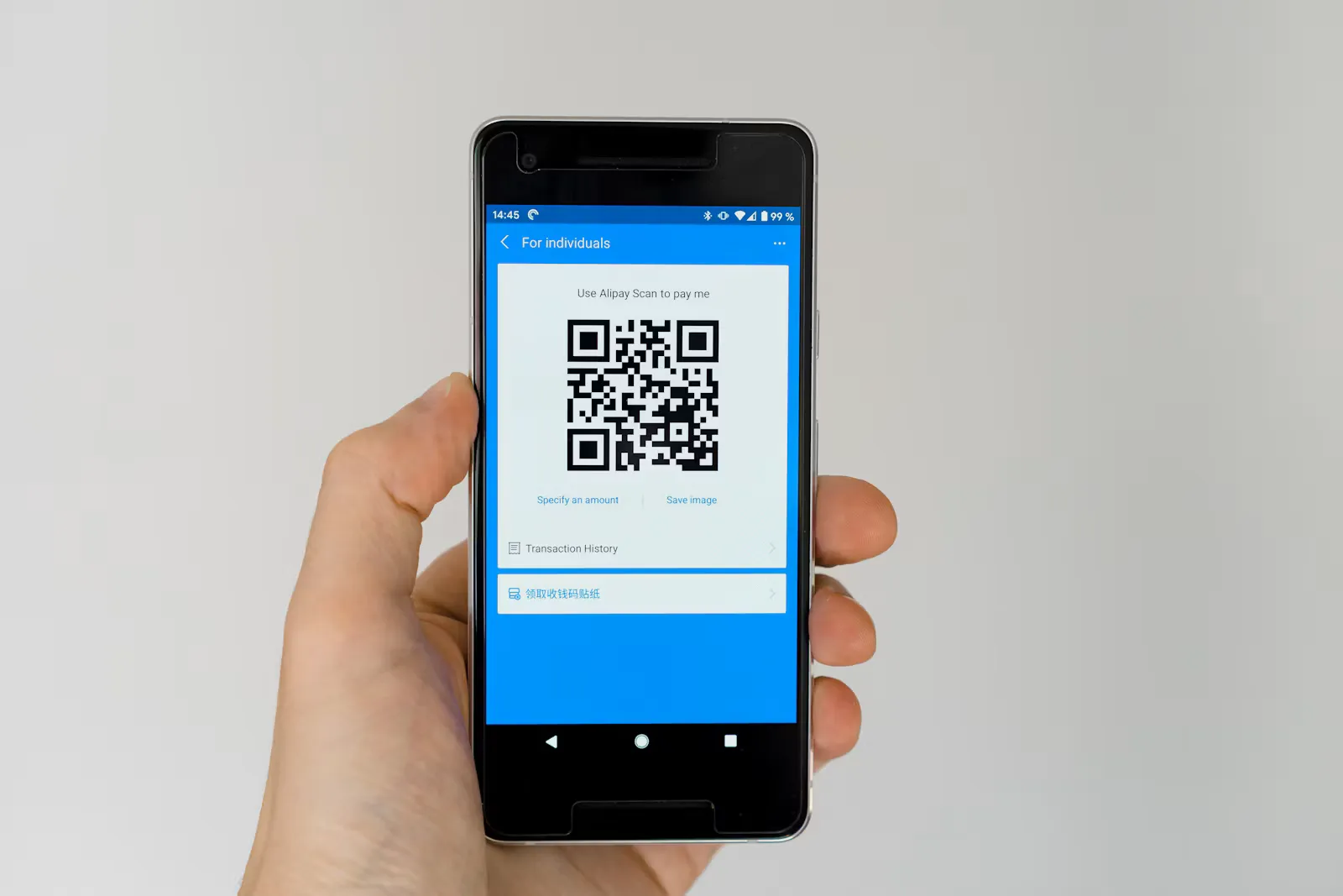 A hand holding a smartphone that shows a QR code on the screen, the way a travel eSIM is usually installed