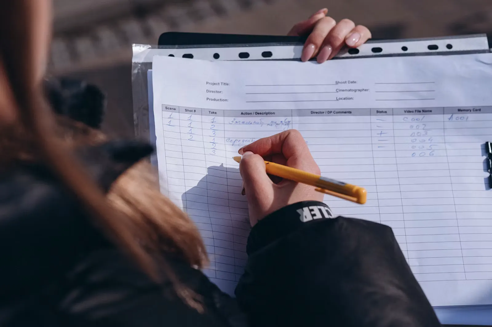 Zwei Hände füllen mit einem gelben Stift ein Formular aus