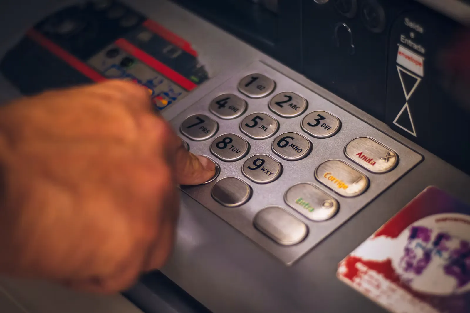 Person hält eine Bankkarte vor einem Geldautomaten