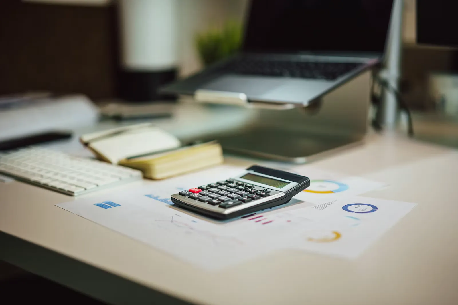 A calculator next to a laptop on a desk, representing budgeting grants and scholarships to fund a clinical placement abroad