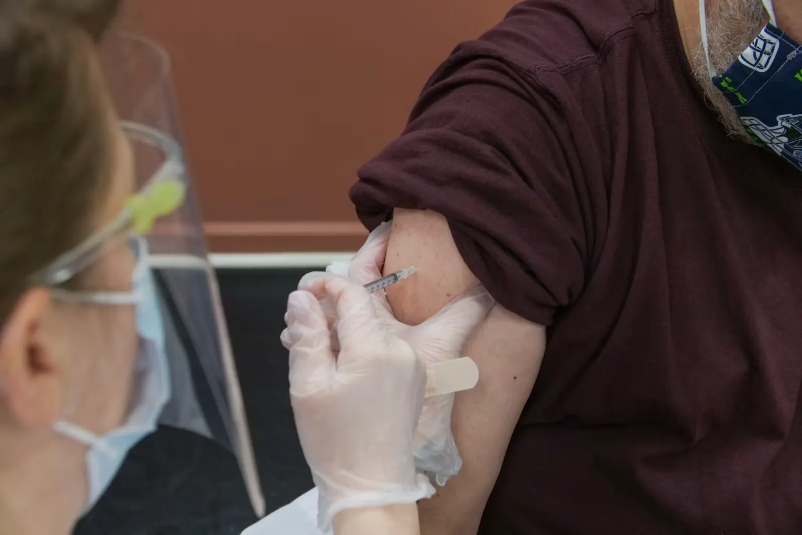 Person mit weissem Verband an der rechten Hand in einem braunen Langarmshirt