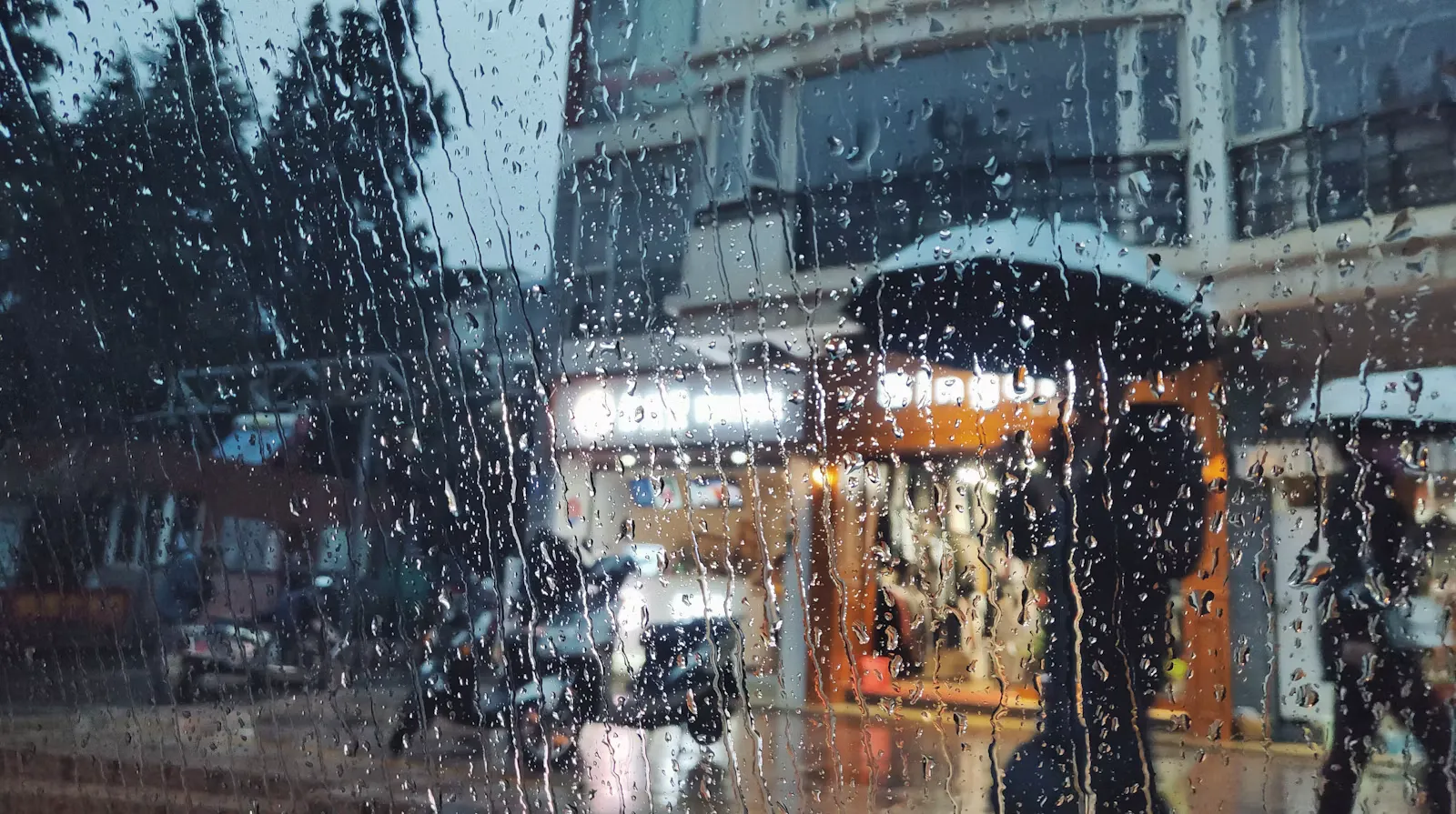 People sheltering under umbrellas on a wet street during heavy monsoon rain