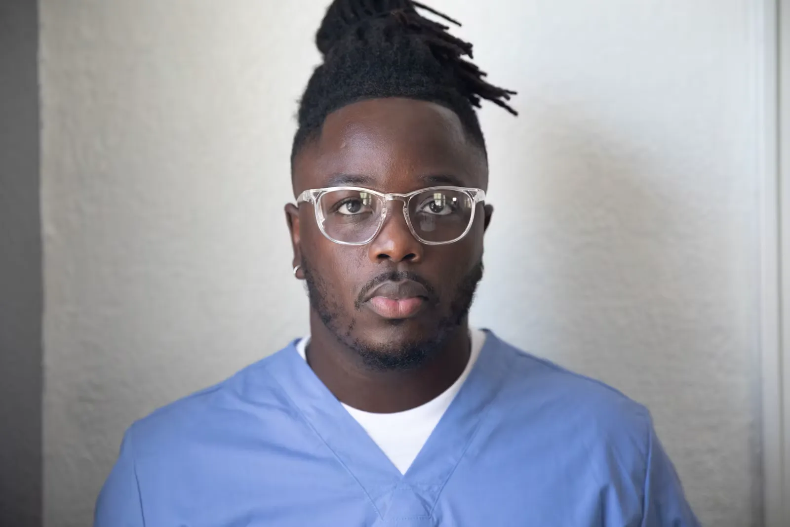 A man in scrubs wearing glasses on the ward