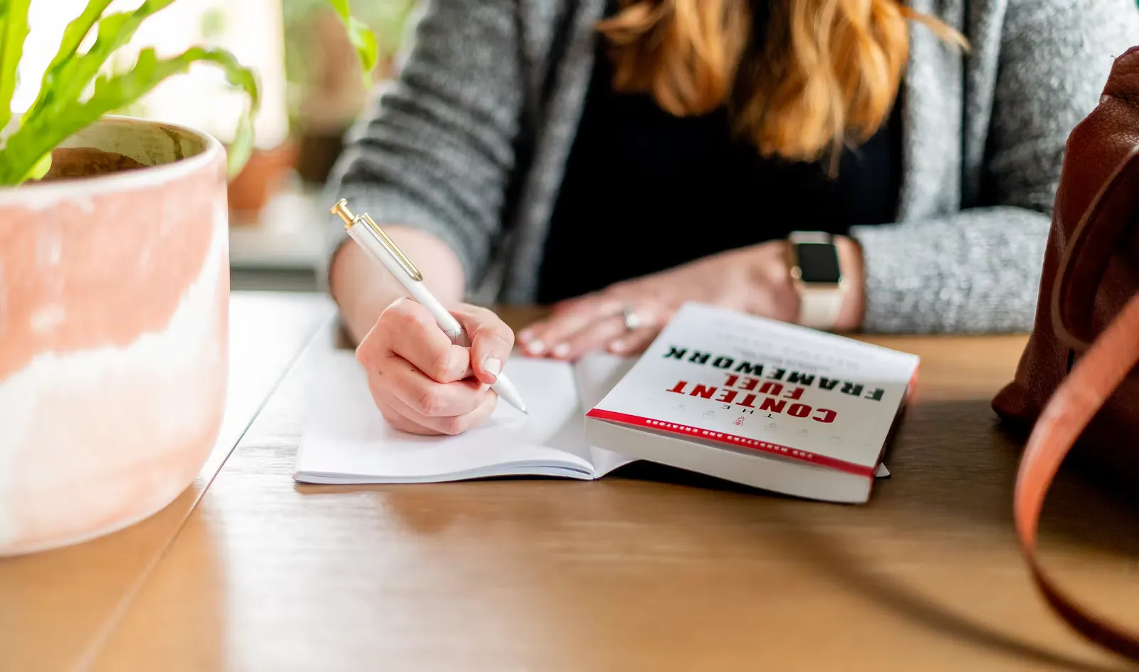 A person in a dark long sleeve shirt writing on white paper