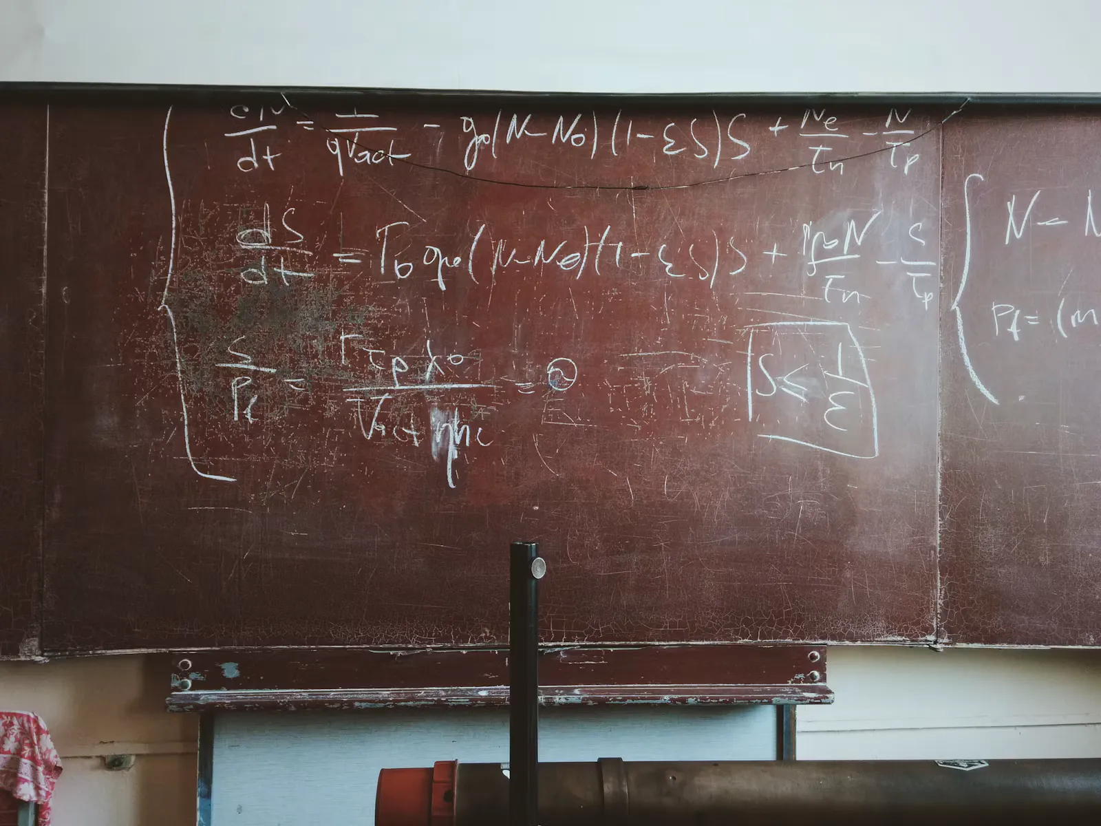Long chalk equations written across a brown classroom blackboard Long chalk equations written across a brown classroom blackboard, the kind of multi-step working JEE asks for and NEET rarely does