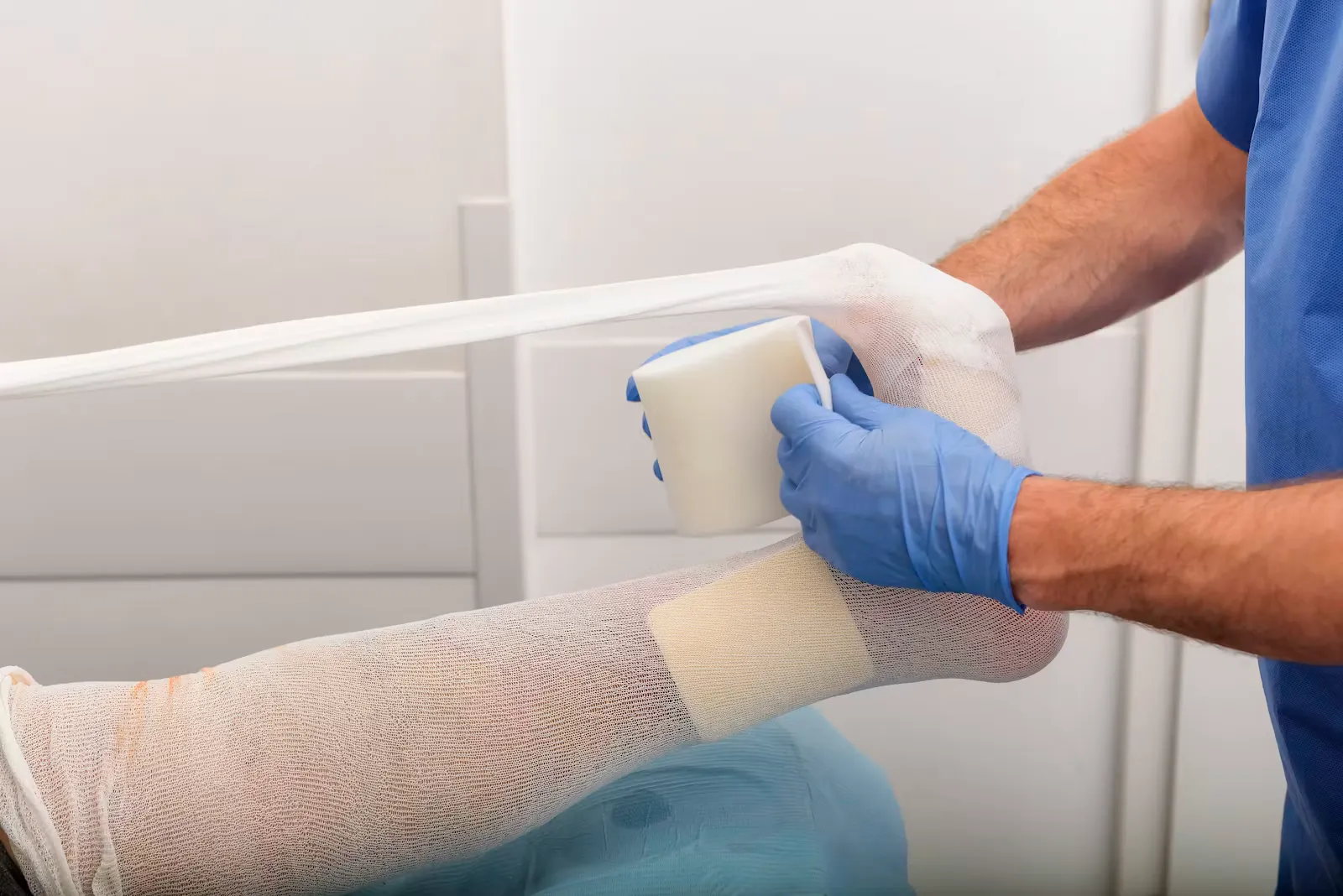 Pflegekraft legt einem Patienten am Fuß einen Verband an