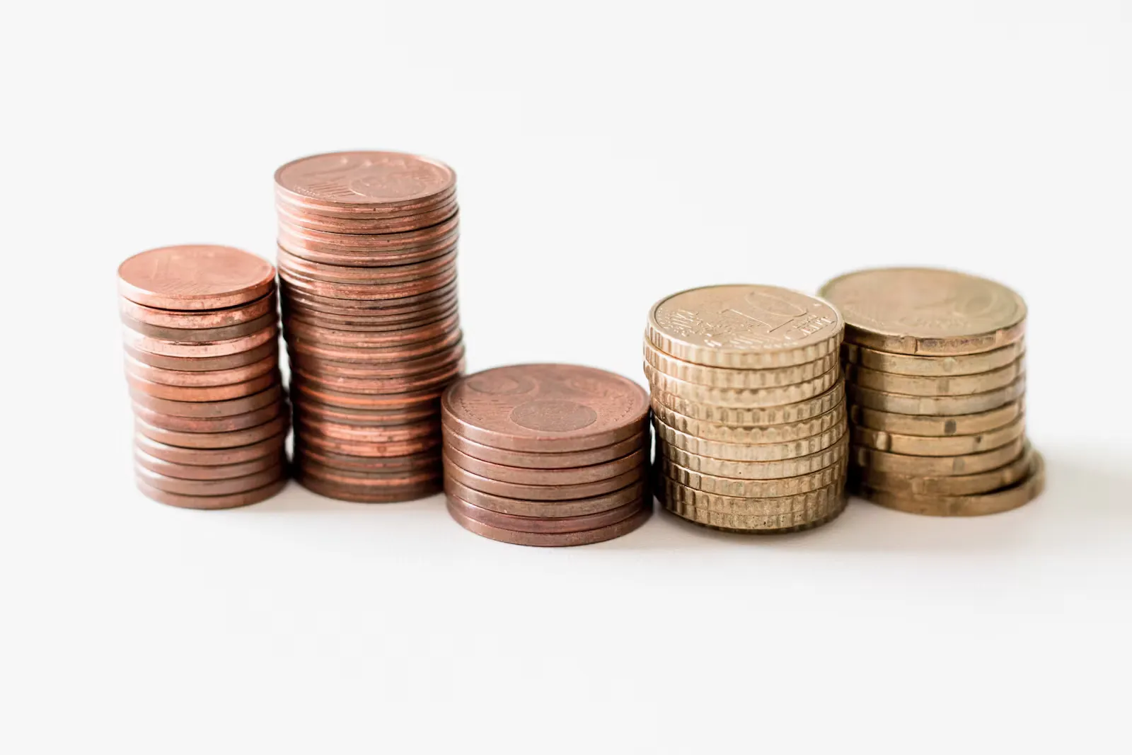 Stacked gold-coloured coins on a white surface, the funding pot for an internship abroad