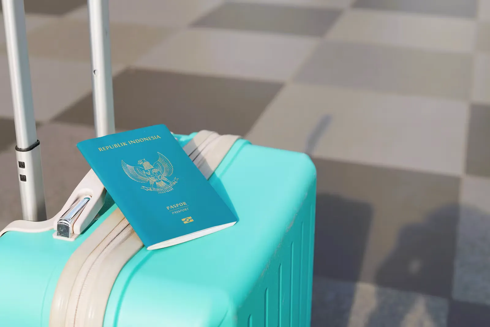 Reisepass liegt auf einem türkisfarbenen Koffer am Flughafen