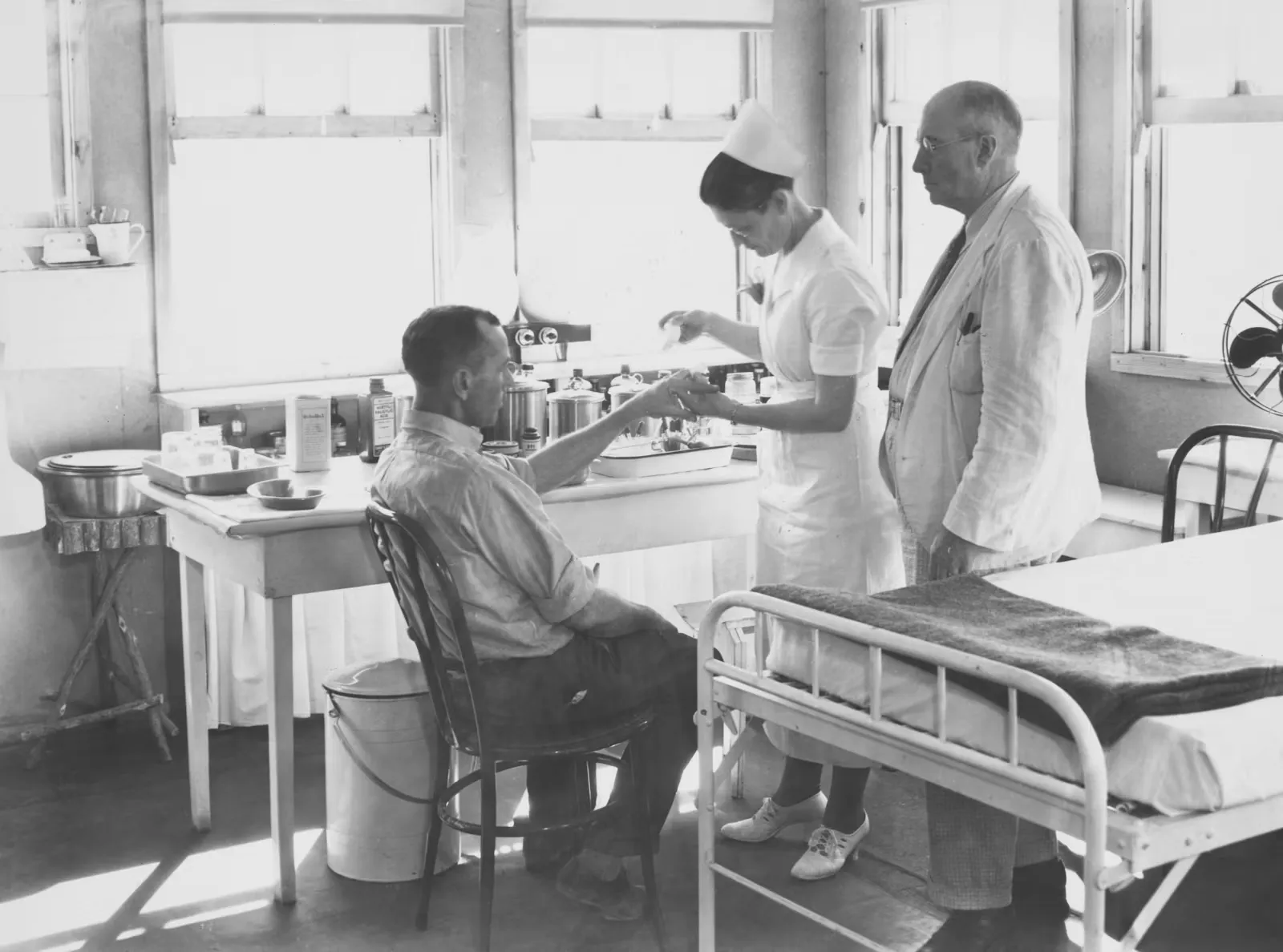 A nurse attending to a patient while a doctor observes