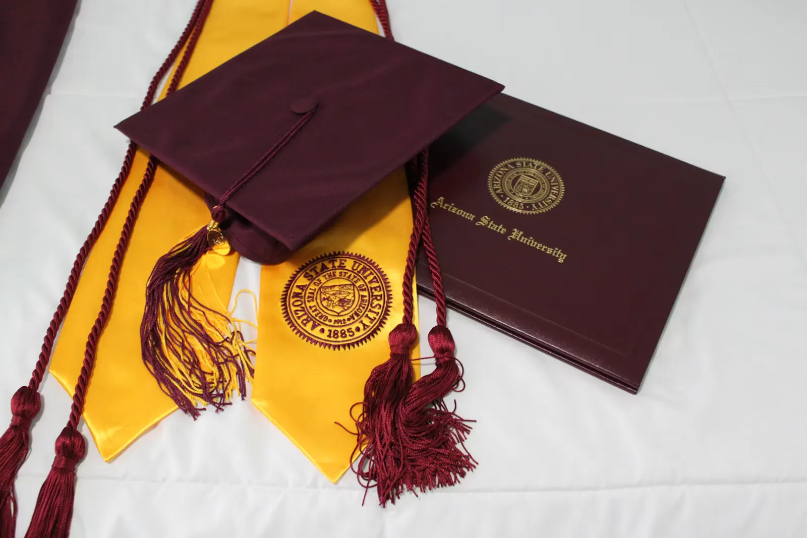A black academic cap lying on yellow fabric after graduation