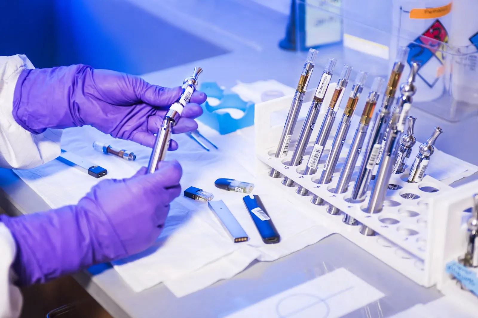 Hände in violetten Einweghandschuhen arbeiten an einem Labortisch mit Probenröhrchen, Symbolbild für mikrobiologische Diagnostik im Spital