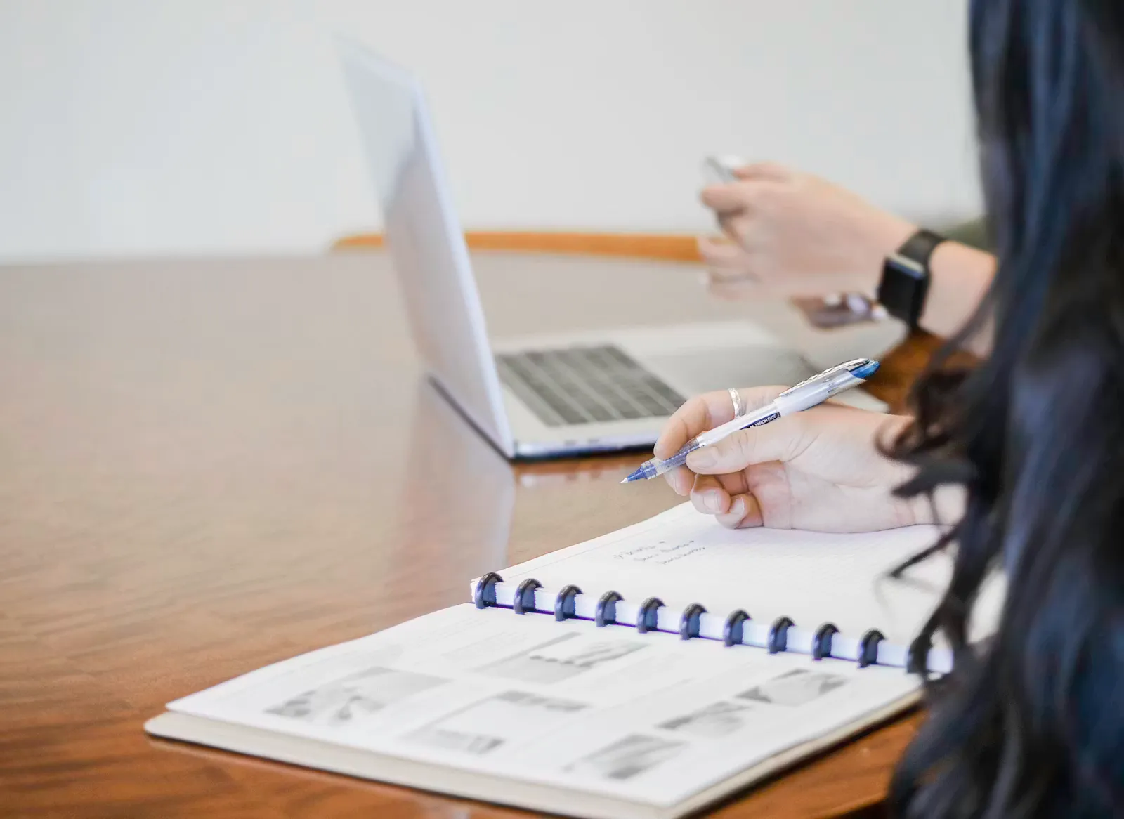 Person schreibt konzentriert mit einem Stift auf Papier, als Symbol für die länderspezifische Vorbereitung einer Bewerbung im Ausland