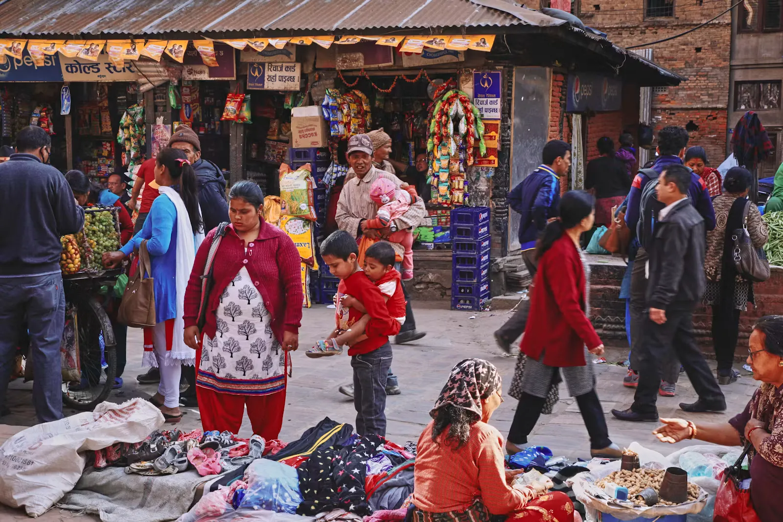 Shoppers crowding a narrow street market lined with stalls and clothing shops in Nepal