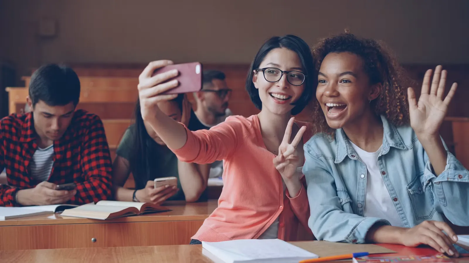 Two smiling students taking a selfie in a classroom