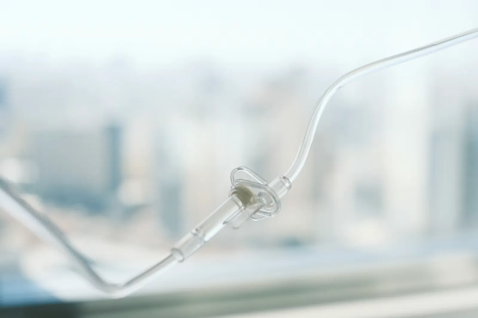 Durchsichtige Infusionsleitung mit Rückschlagventil vor einem unscharfen, hellen Spitalfenster, Symbolbild für die Akutpflege im Auslandspraktikum Pflege